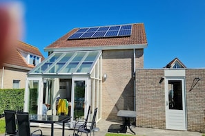 A house with a solar panel roof, a glass-enclosed patio, and a brick exterior. - Relaxing Zeeland Escape (Breskens)