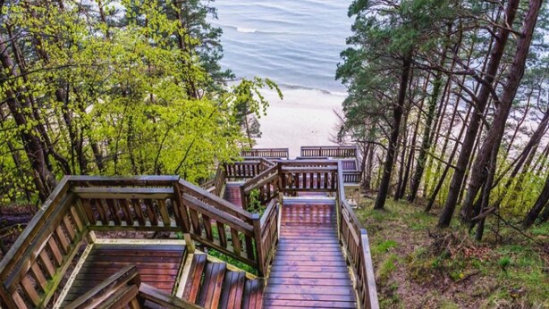Une terrasse en bois qui mène à une plage, avec vue sur l’océan.