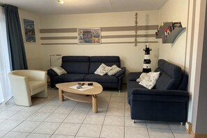 A living room with a sofa, armchair, coffee table, and a wall with a picture.