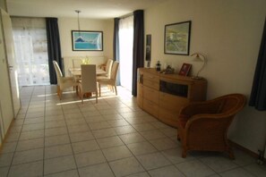 Un comedor con una mesa y sillas, un aparador de madera y dos cuadros en la pared.