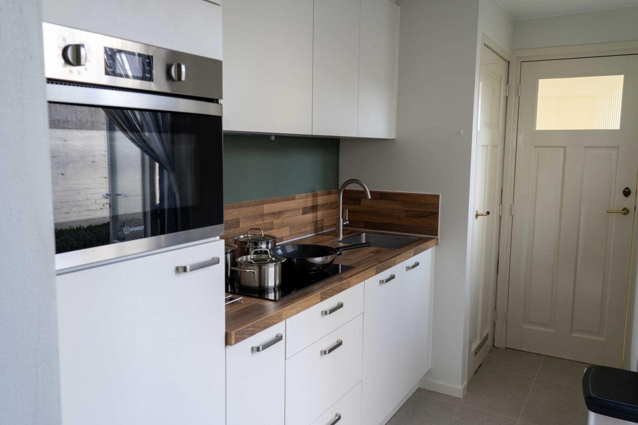 Una cocina compacta con horno integrado, cocina y lavamanos.
