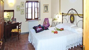Ein Schlafzimmer mit Bett, Schreibtisch, Stuhl, Fenster und Heizkörper.