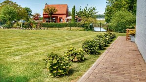 Une pelouse bien entretenue, avec un chemin en briques menant à un bâtiment doté d’un toit rouge.
