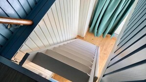 Une pièce avec un plancher en bois, un plafond blanc et une fenêtre donnant sur l’extérieur.