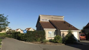 A residential street with houses, a clear sky, and a blue directional sign. - Pet-Friendly Coastal Home (Breskens)
