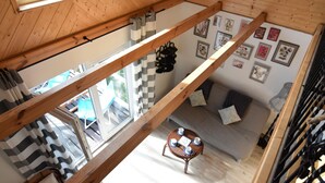 A high-ceilinged wooden room with a loft area, a dining table with chairs, and a sofa. - Holiday Home Near Lake Mausz With Sauna (Parchowo)