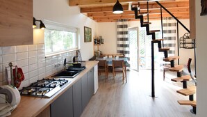 A modern kitchen with a central island, wooden ceiling beams, and a staircase leading to a dining area. - Holiday Home Near Lake Mausz With Sauna (Parchowo)