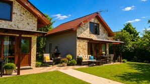 A two-story house with a stone facade, a red-tiled roof, and a patio with outdoor furniture. - Seaside Holiday Home Swinoujscie (Swinoujscie)