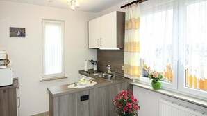 Een moderne keuken met een centraal eiland, een raam met gordijnen, een radiator en een kleine plant.