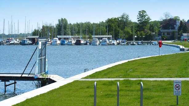 Een jachthaven met afgemeerde boten, een gazon en een verboden hondensign.