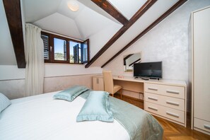Un dormitorio con cama, escritorio, silla, televisor y armario.