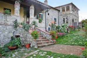 A stone building with a garden and steps leading to a door. - Country House in Tuscany With Panoramic Views (Chiusdino)