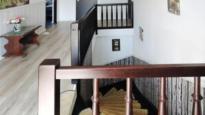 A wooden staircase with a handrail, a wall-mounted light fixture, and a small framed picture.