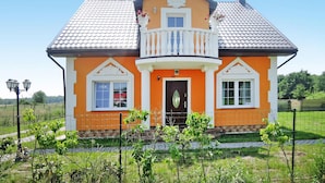 A two-story house with a balcony, a front door, and a small window on the second floor.