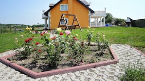 A yellow house with a white porch and a swing set in the garden.