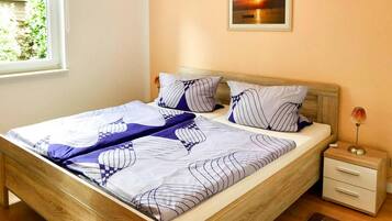 A neatly made bed with striped bedding, a wooden headboard, and a nightstand with a lamp.