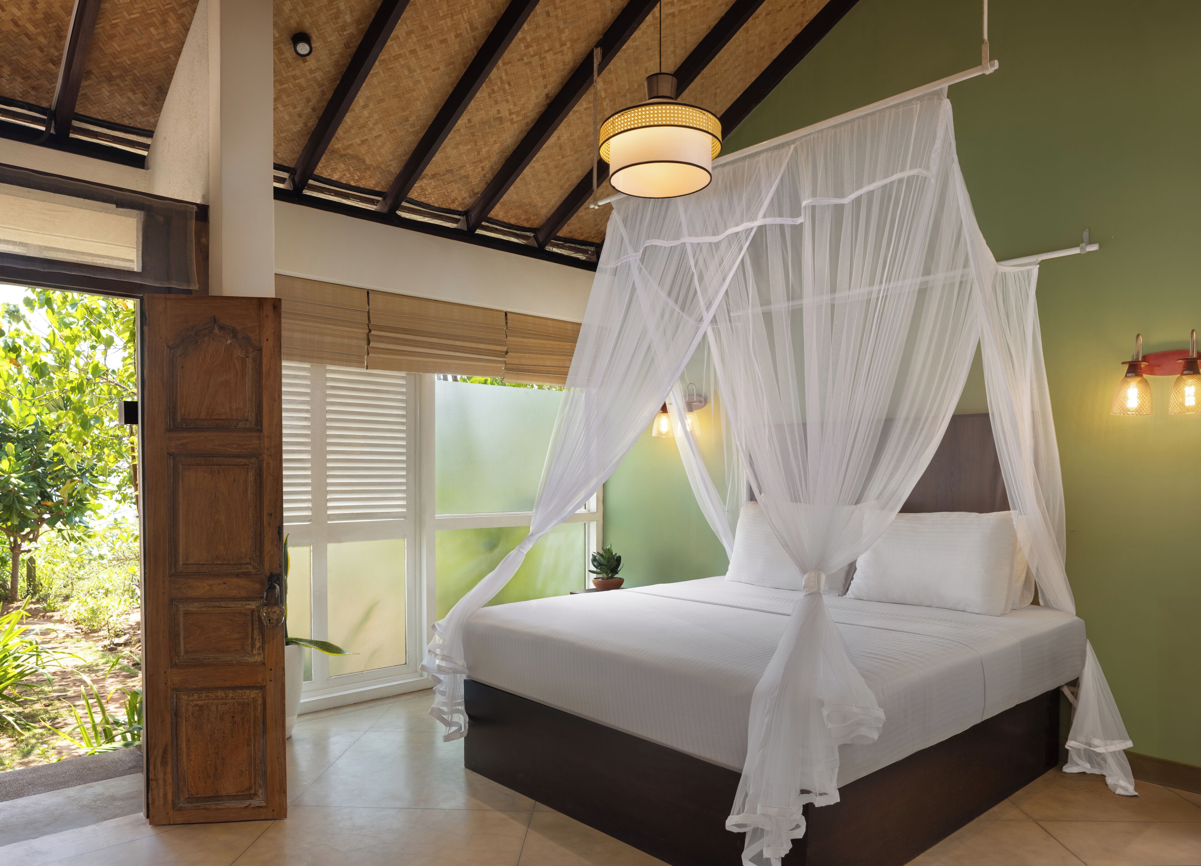 Un dormitorio con cama a dosel, puerta de madera y vista a zonas verdes.