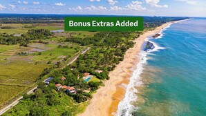 Una propiedad costera con playa, piscina y vegetación circundante.