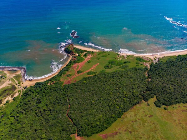An aerial view of a coastal area with a beach, dense forest, and rocky outcrops. - Ravana Garden Sustainable Luxury Boutique Hotel (Ambalantota)