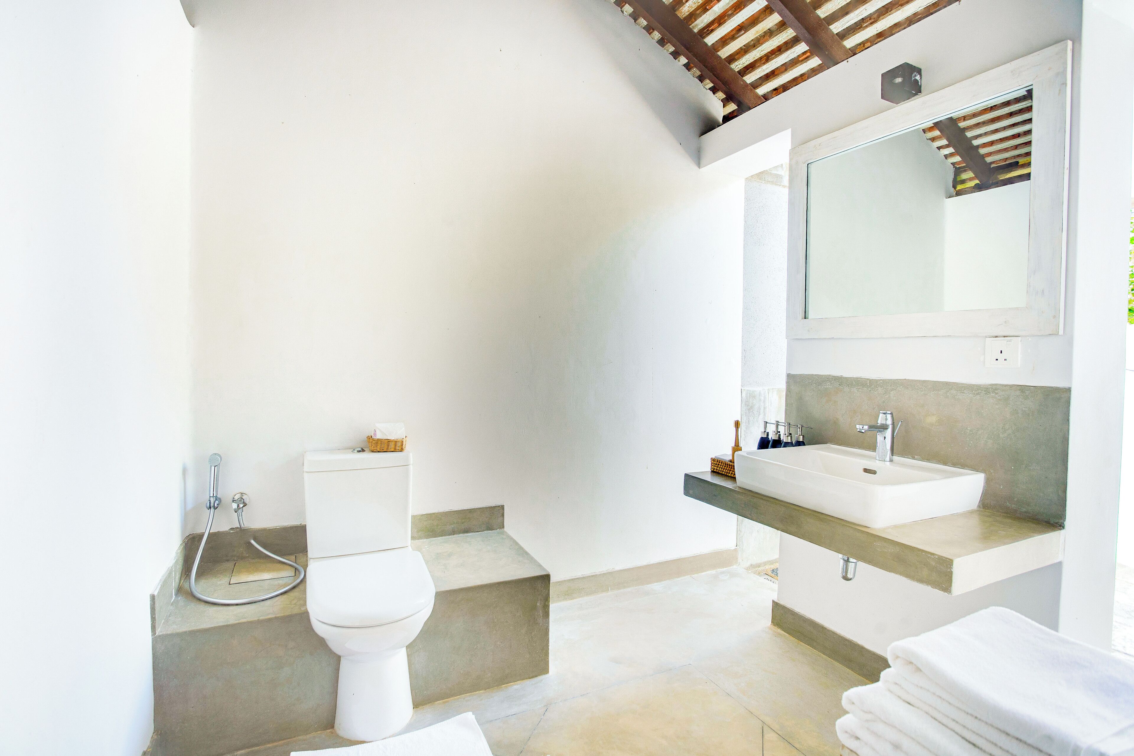 Ein modernes Badezimmer mit Toilette, Waschbecken und Treppenstufen zu einem Duschbereich.