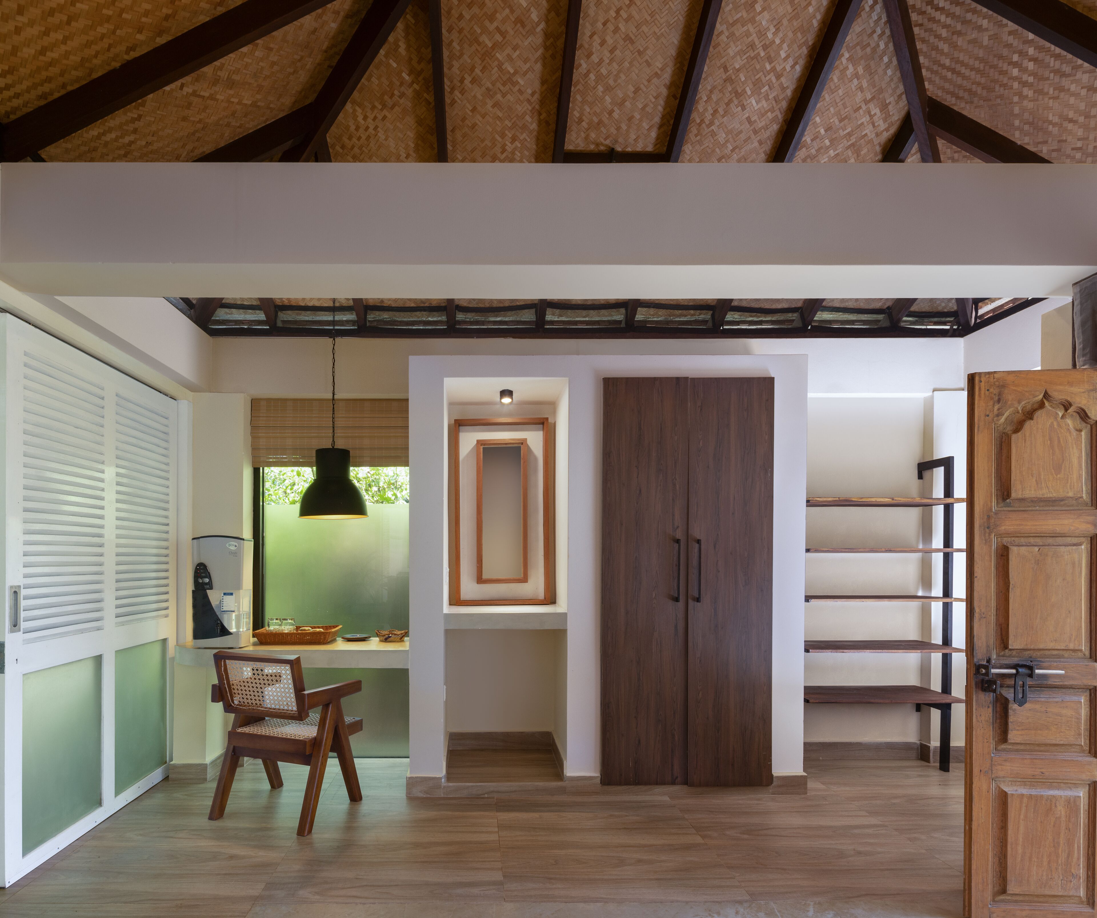 A modern kitchen with a wooden ceiling, a dining area with a chair, and a built-in cabinet.