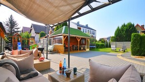 An outdoor patio area with a covered seating area, a children's play structure, and a barbecue setup. - Comfortable 3-room Apartment Close to the sea (Ustronie Morskie)
