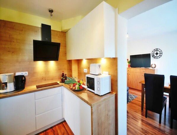 A compact kitchen with white cabinets, a microwave, a toaster, and a coffee maker.