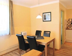 A dining area with a wooden table and four black chairs, a pendant light, and a framed picture on the wall. - Bungalows am Vordersee, Dobbrikow (Nuthe-Urstromtal)