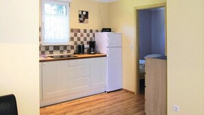 A compact kitchen with white cabinets, a coffee maker, and a refrigerator. - Bungalows am Vordersee, Dobbrikow (Nuthe-Urstromtal)