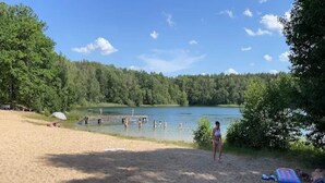 A sandy beach with a lake, trees, and a dock. - Bungalows am Vordersee, Dobbrikow (Nuthe-Urstromtal)