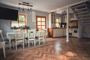 Un'ampia cucina con pavimento in parquet a spina di pesce, mobili bianchi e un'isola centrale.