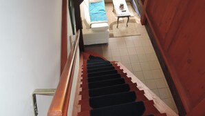 A wooden staircase with black carpeted steps leading to a bedroom with a bed and a small table. - Holiday Home Sulomino With Private Beach (gmina Wolin)