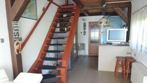 A spacious living area with a wooden staircase, a kitchen with a TV, and a dining area with stools. - Holiday Home Sulomino With Private Beach (gmina Wolin)