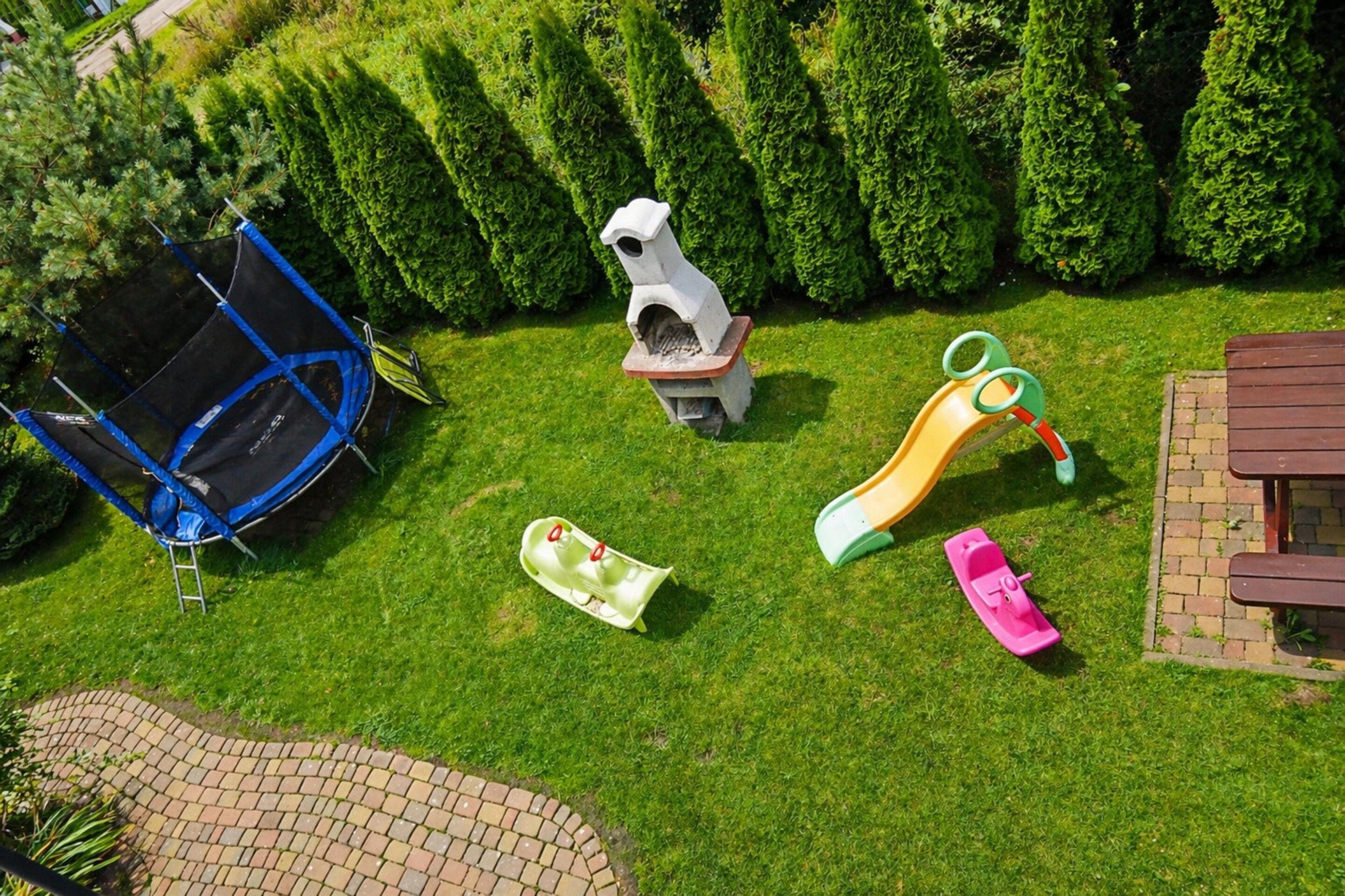 A playground with a trampoline, slide, and swings.