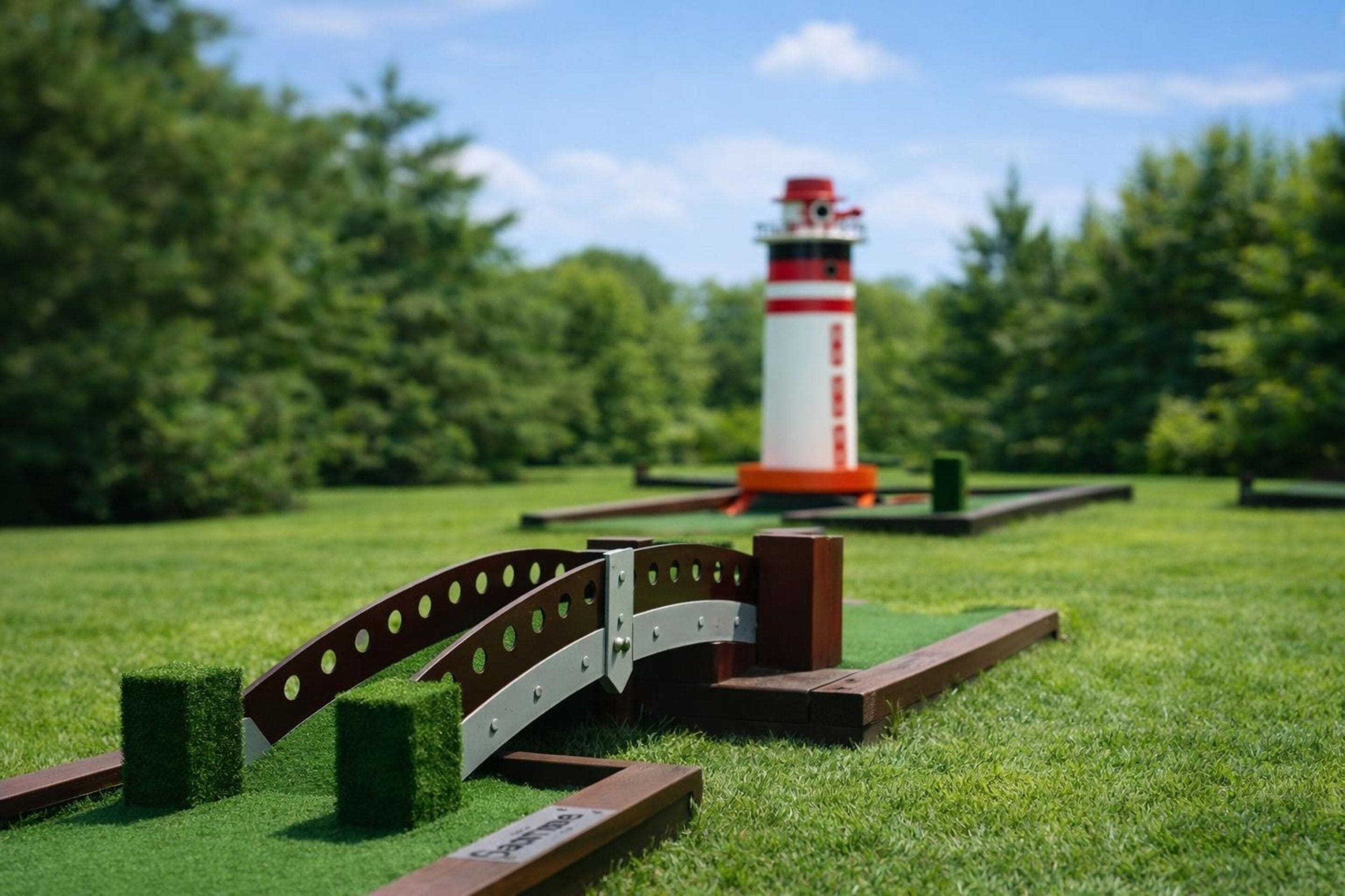 A miniature model of a bridge over a body of water with a lighthouse in the background.