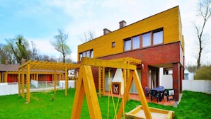A modern house with a wooden swing set in the backyard. - Spacious Holiday Home With Private Garden (Mielno)