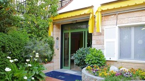 A building with a green door, yellow awning, and a stone facade. - Apartment in Pietra Ligure (Pietra Ligure)