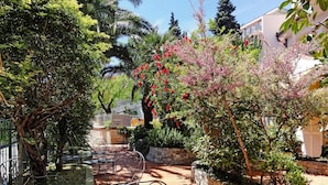 A patio area with outdoor seating, surrounded by lush greenery and flowering plants. - Apartment in Pietra Ligure (Pietra Ligure)