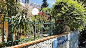 A stone wall with a sign reading "Residence de Fiori" and a green metal fence with plants. - Apartment in Pietra Ligure (Pietra Ligure)