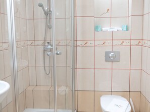 Un baño con ducha acristalada, inodoro y lavamanos.
