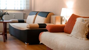 Un salon moderne avec un canapé, une petite table sur laquelle est posé un vase, et une lampe.