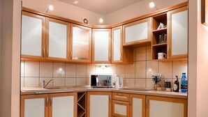 Une cuisine moderne avec des meubles en bois, un four encastré et un plan de travail sur lequel se trouvent une bouilloire et une machine à café.