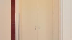 Un armario cerrado color beige con tiradores plateados, una alfombra roja y un marco de puerta blanco.