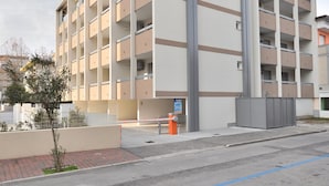 Un edificio de varios pisos con un diseño arquitectónico moderno, que presenta una serie de balcones y un acceso con puerta de reja.