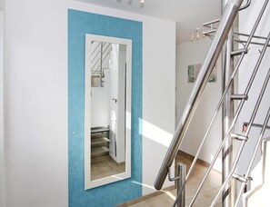A modern interior with a blue accent wall, a metal staircase, and a door leading to a stairwell. - Ferienhaus, Boiensdorf (Boiensdorf)