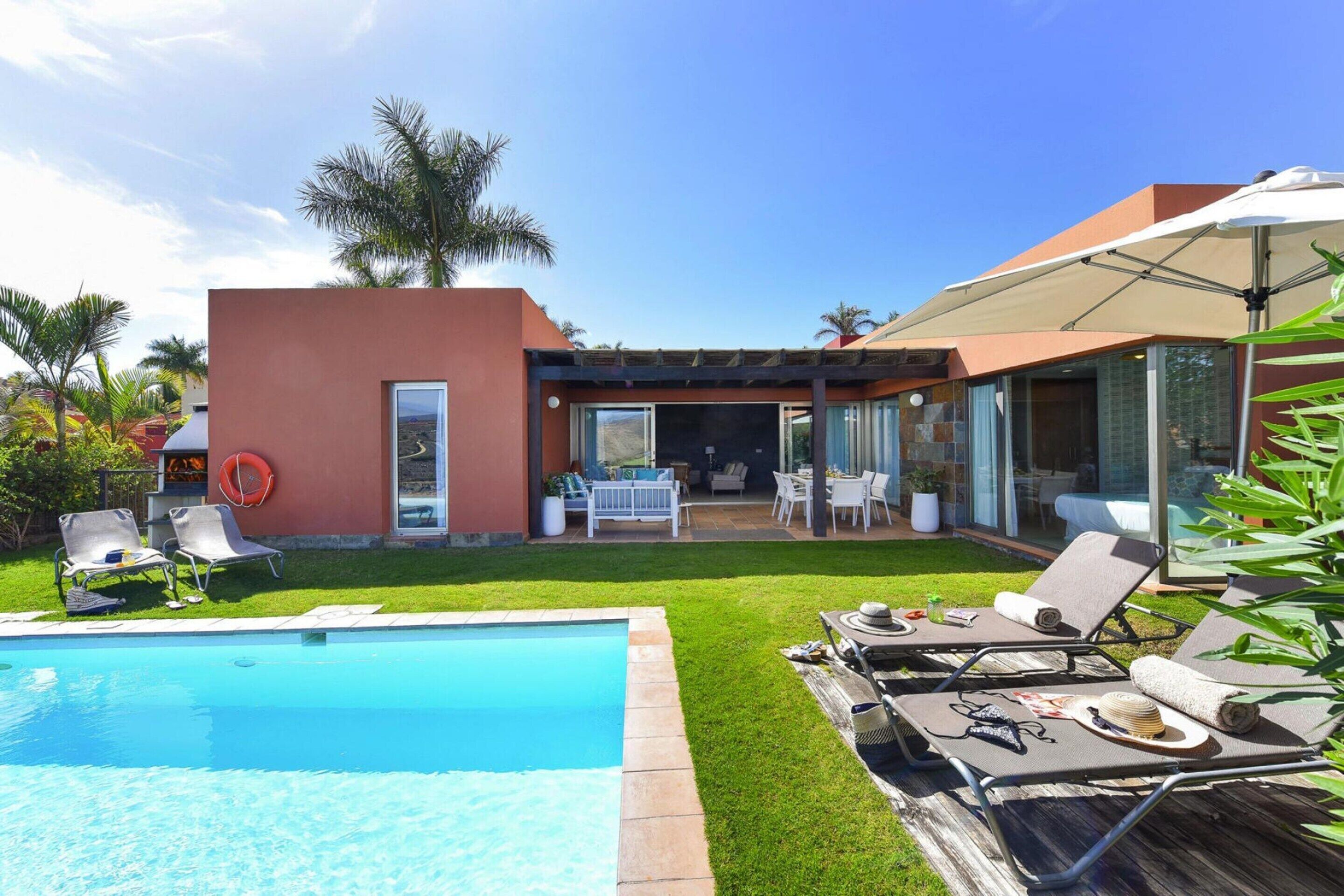 Ett modernt hus med en swimmingpool, utomhusmöbler och en uteplats.