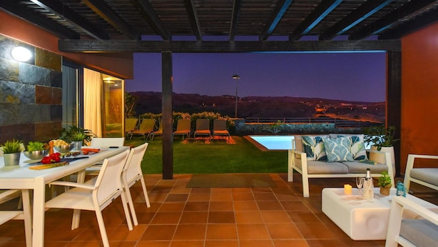 Um pátio externo com mesa de jantar, cadeiras e piscina.