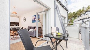 An outdoor patio with a table and chairs, a sliding glass door leading to a kitchen, and a white exterior wall. - Apartment With Swimming Pool, Terrace, Pobierowo (Rewal)