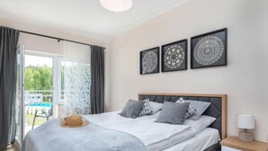 A bedroom with a bed, a nightstand, a lamp, and three framed wall art pieces. - Apartment With Swimming Pool, Terrace, Pobierowo (Rewal)