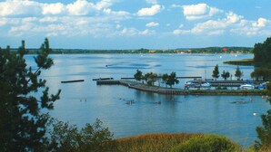 A calm lake with docks and boats, surrounded by trees and a clear sky. - Hausboot auf der Peene, Demmin (Demmin)